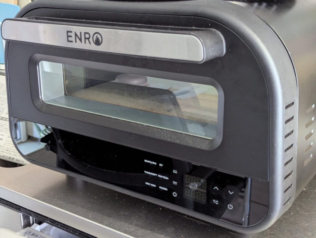 卓上型の黒いピザ窯「ENRO」。ガラス窓から内部の石板が見え、デリピックスのオープンサンドを焼くために使用された調理器具。