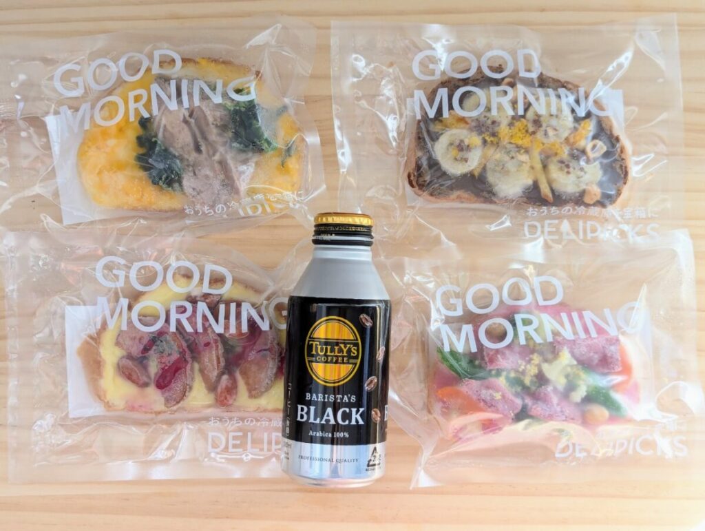 DELIPICKSの冷凍オープンサンド4種類を並べた写真。中央にはタリーズコーヒーのボトル缶が置かれており、大きさがわかる。