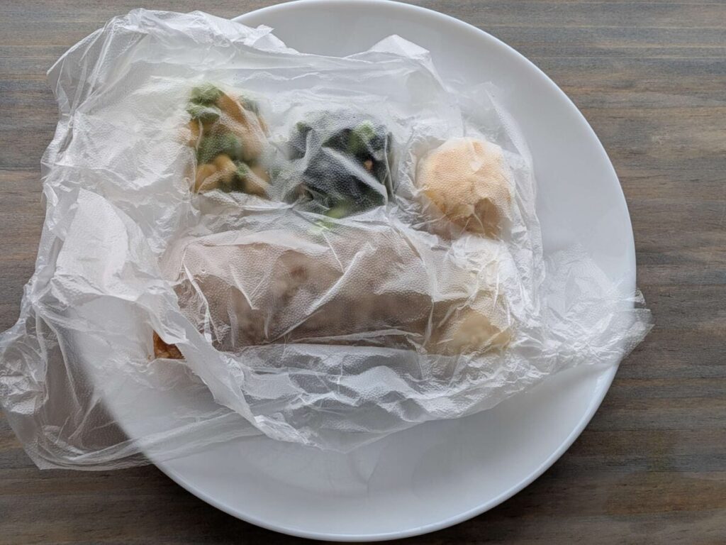 ナッシュの冷凍弁当をプレスンシールで包み、圧縮したものをお皿に移した様子
