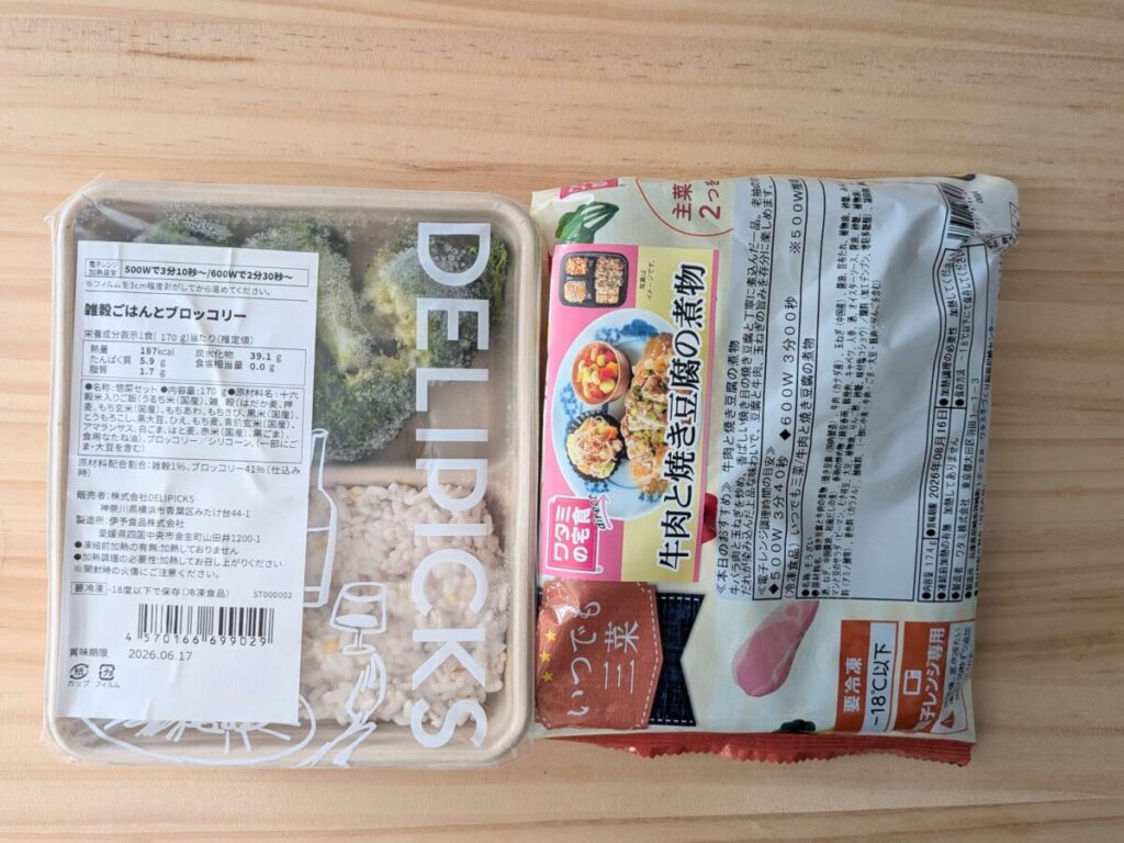 ワタミ宅食ダイレクト「牛肉と焼き豆腐の煮物」のパッケージを折った様子と、DELIPICKS「雑穀ごはんとブロッコリー」の容器を並べて撮影した比較画像。冷凍弁当のサイズ感が分かる配置。