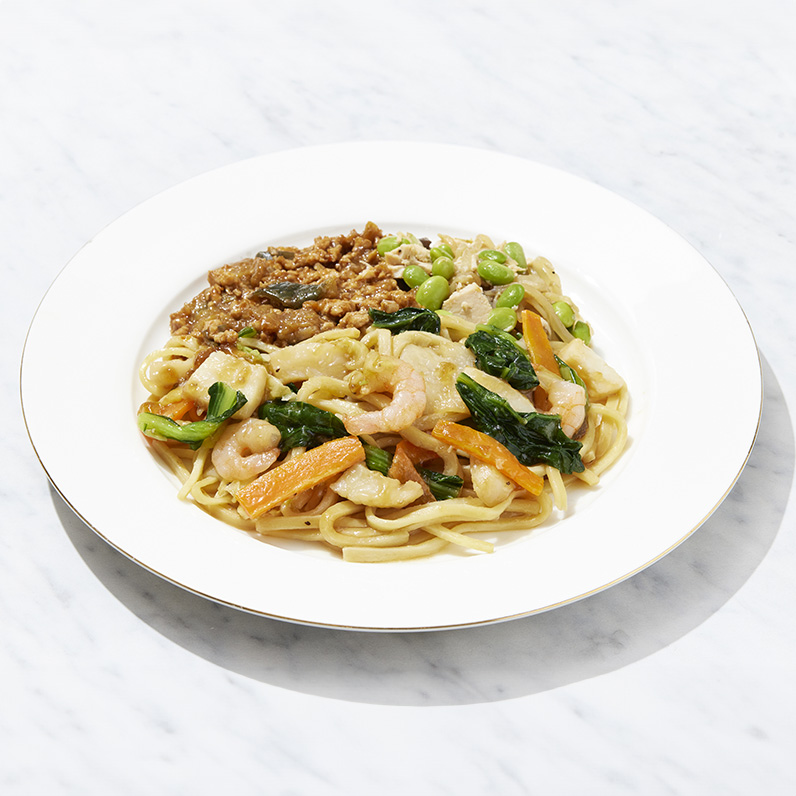 マッスルデリの海鮮あんかけ焼きそばセット。 エビやイカ、青菜、にんじんなどの具材をあんかけに仕立てた麺料理で、副菜にそぼろ炒めと枝豆の和え物が添えられている