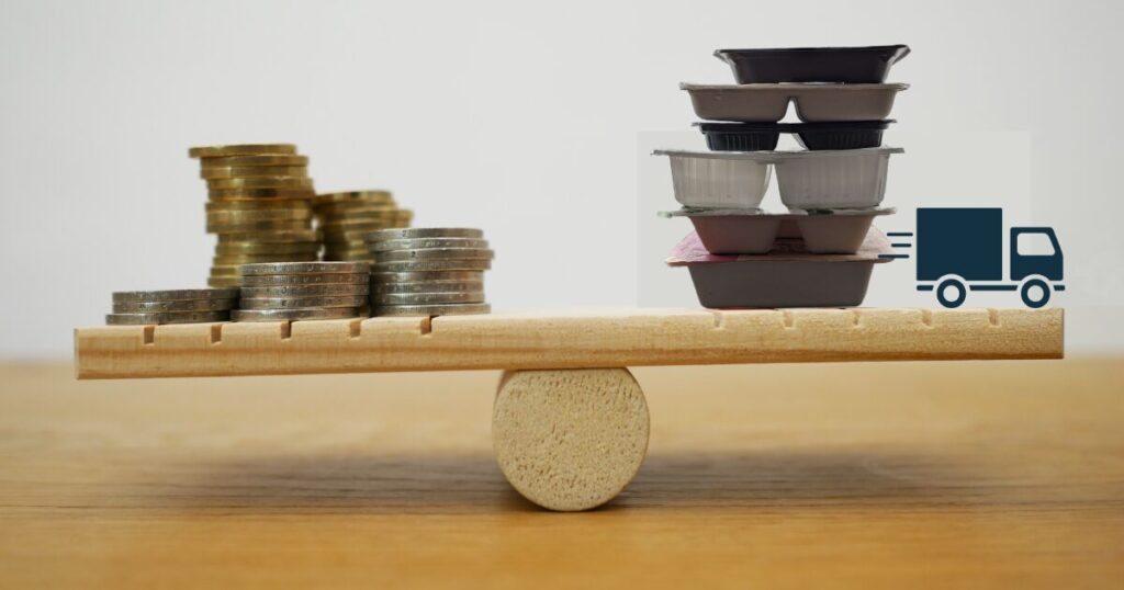 コインと宅配弁当の容器がシーソーに乗った写真。宅食サービスの料金やコスパのバランスを表すイメージ。