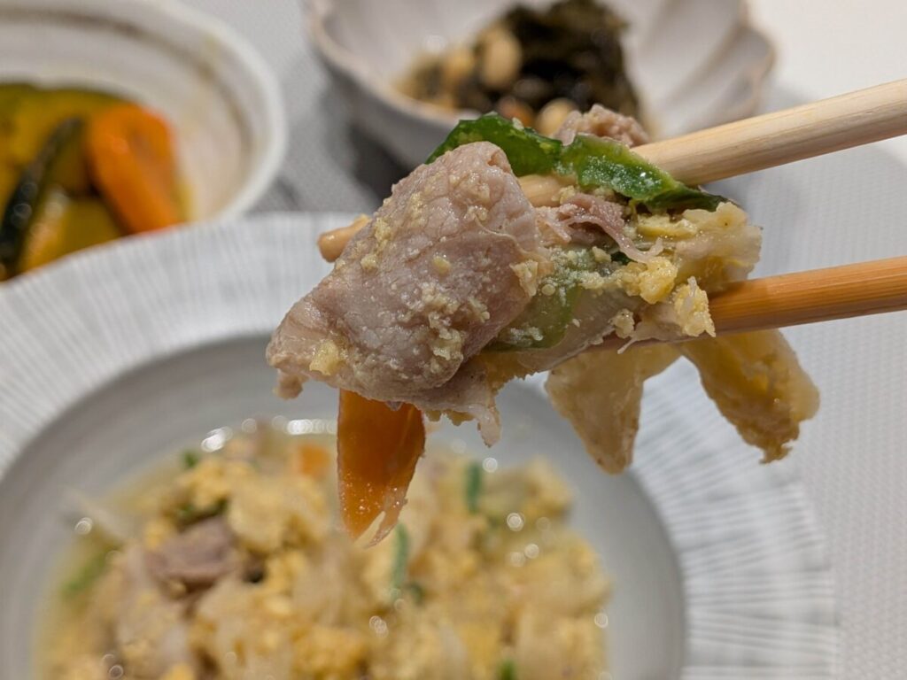 わんまいる大山豚のチャンプルーアップ写真。豚肉・卵・ピーマン・にんじん・キャベツを箸で持っている。