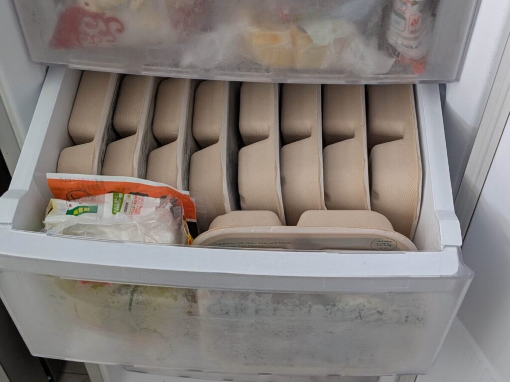 冷凍庫の引き出しに、GREEN SPOON（グリーンスプーン）のデリ弁当10食を縦に並べて収納し、空いたスペースに他の冷凍食品を入れている様子
