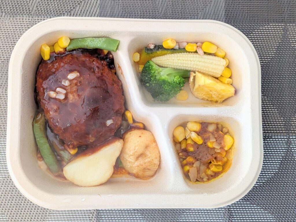 グリーンスプーンデリ弁当特製デミグラスハンバーグ。サイドファッロとコーンのカレーと温野菜サラダ