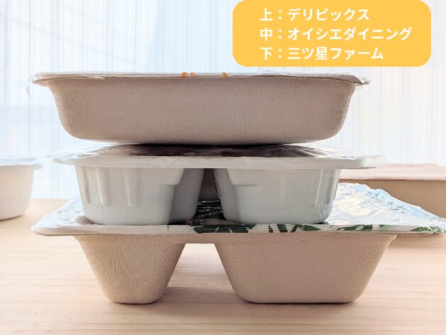 デリピックス、オイシエダイニング、三ツ星ファームの冷凍弁当容器を重ねて高さを比較した写真。