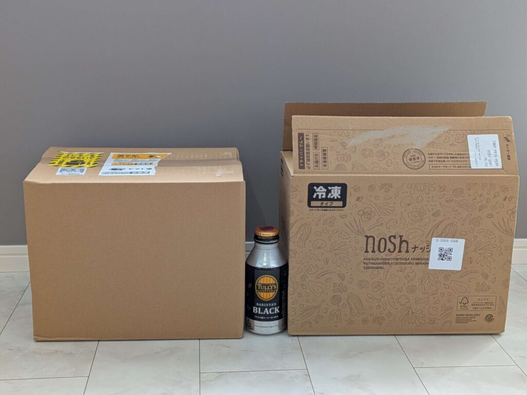 左にオイシエダイニング、右にナッシュの配送箱を並べ、中央にタリーズのボトル缶を置いて大きさを比較した写真。