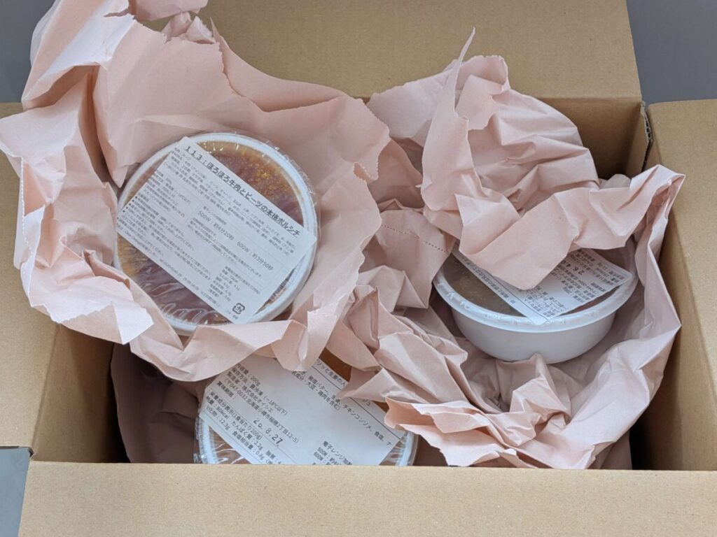 オイシエダイニングの冷凍スープが段ボール箱に緩衝紙と一緒に梱包されている様子。