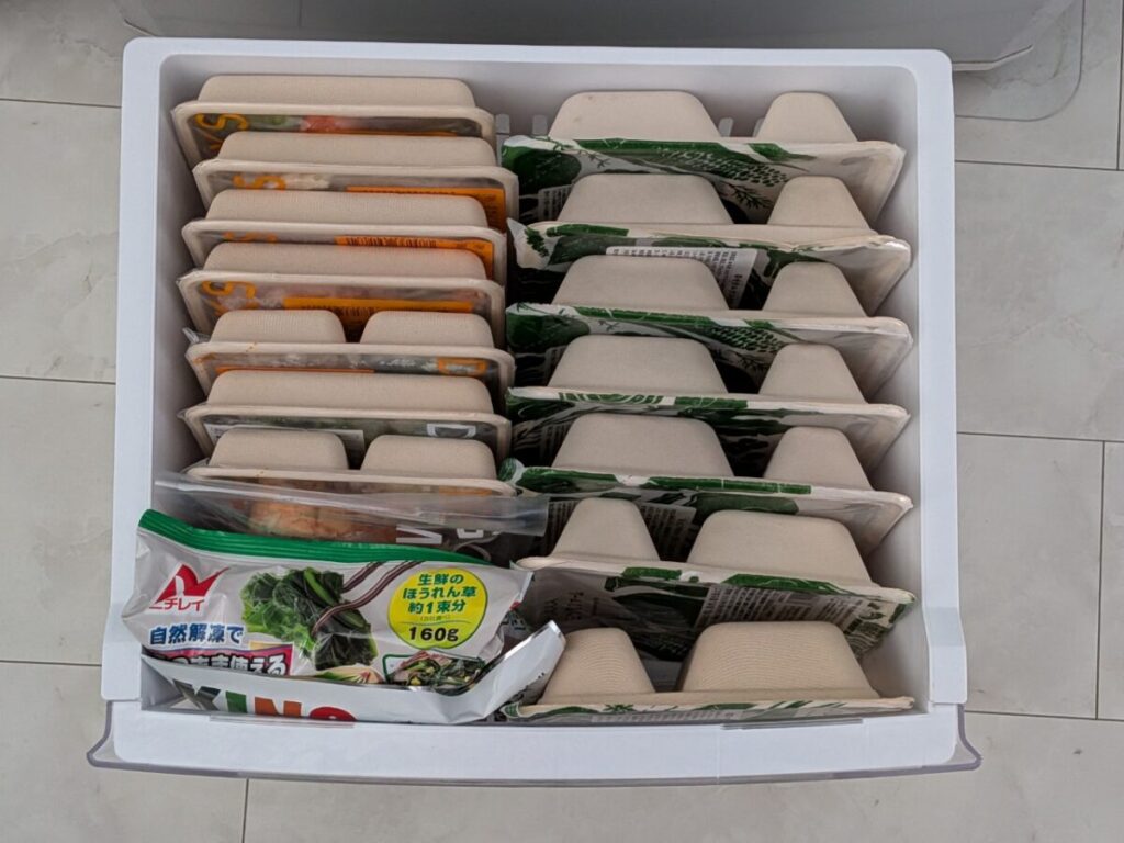 三ツ星ファームとデリピックスの冷凍弁当を冷凍庫に並べて収納している写真。容器サイズと収納しやすさを比較している実例。