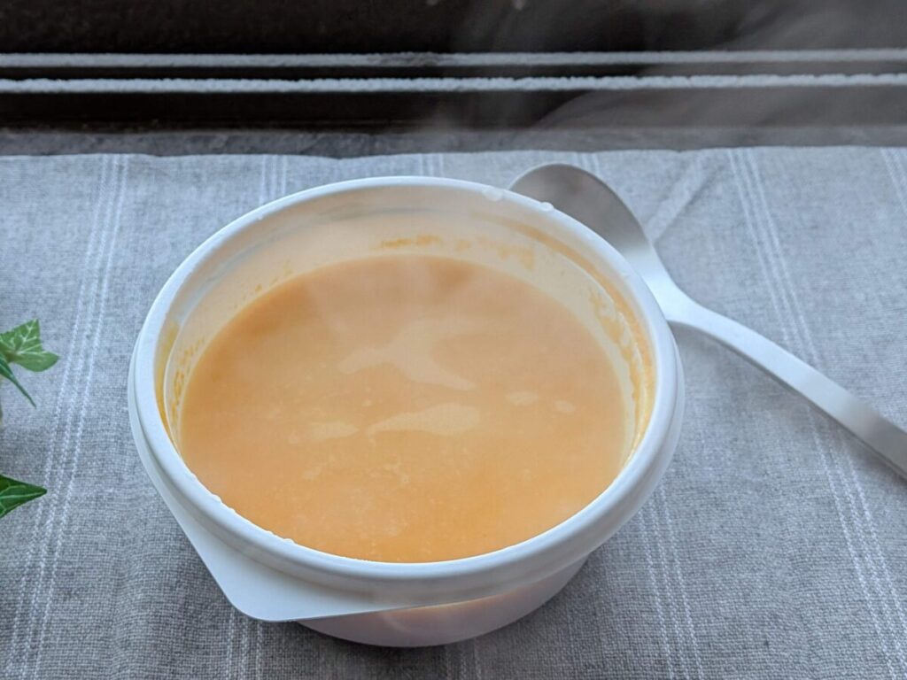 ランチョンマットに置かれたにんじんのポタージュ。スープの脇にはスプーンが置かれている。