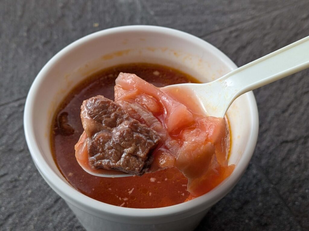 オイシエダイニングのほろほろ牛肉とビーツの本格ボルシチの具材をスプーンですくっているアップ写真