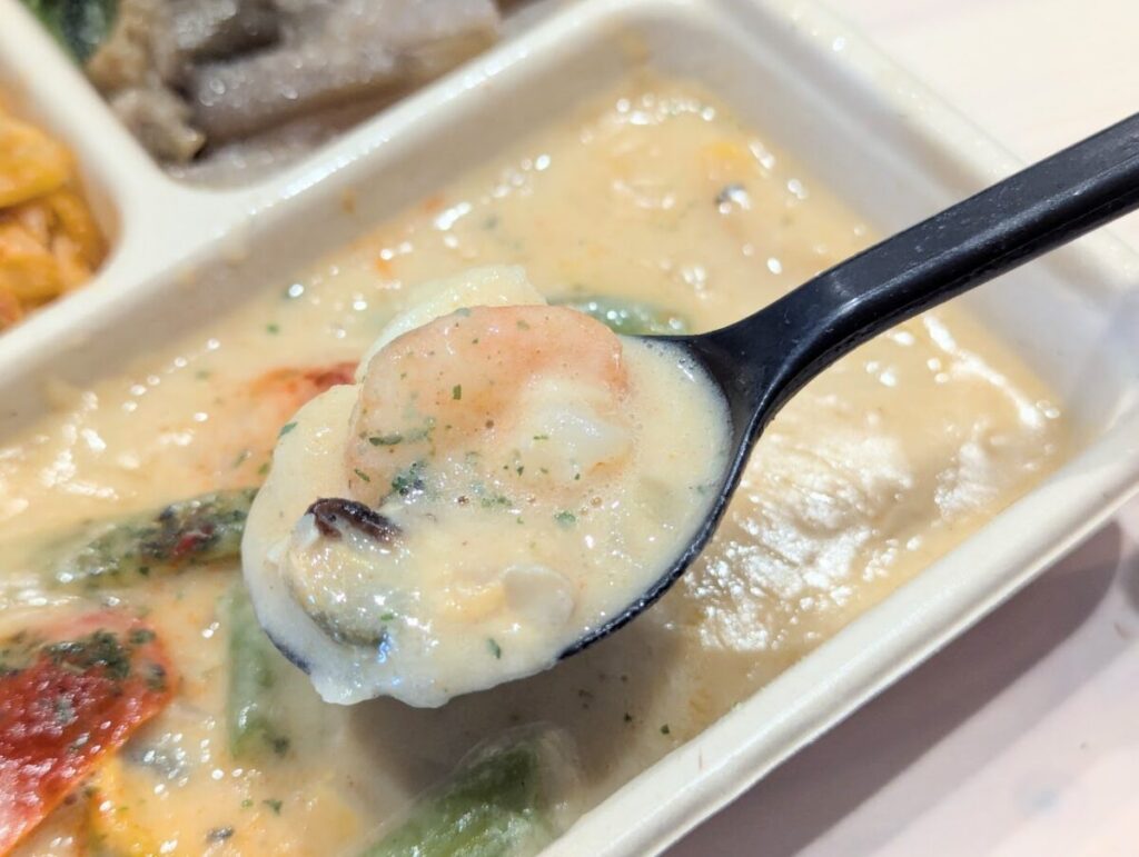 デリピックス魚介の本格ホワイトカレー 濃厚クリーミー仕立てのカレーをスプーンですくっている様子。