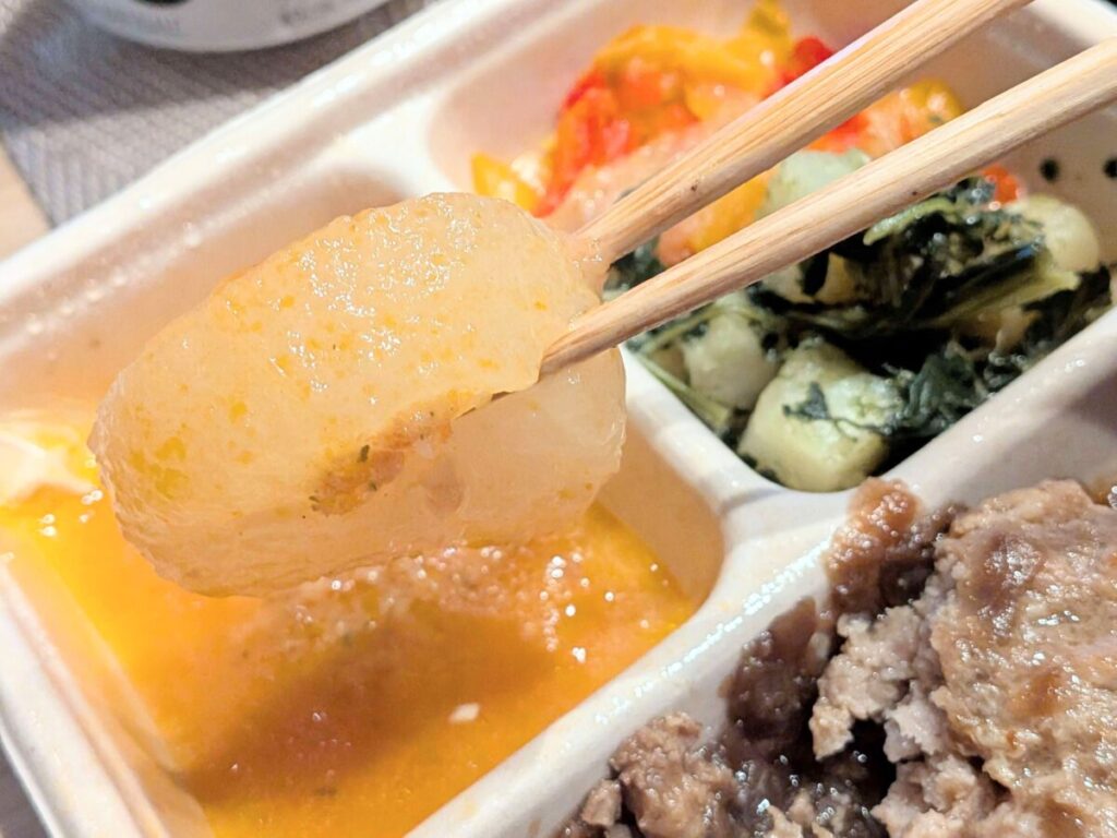 デリピックス飴色玉ねぎのシャリアピンソースの副菜のピザ風大根を箸で持っているアップ画像