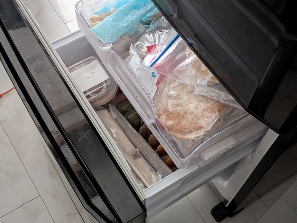 冷凍庫の引き出しを開け、実際に食材やパックが詰まっている様子。容器の重なり方や隙間の使い方の参考になる写真。